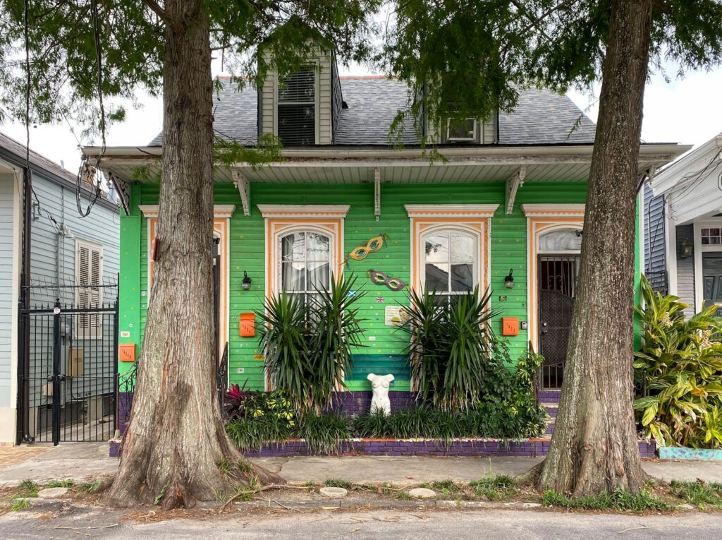 a green house with a white cat in front of it