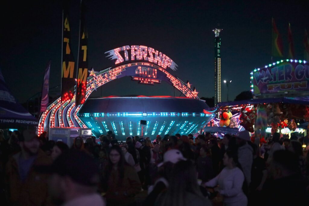 a crowd of people standing around a carnival at night